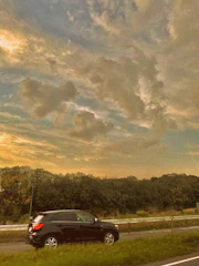 A black Ford Expedition XL driving smoothly along a scenic coastal highway at sunset.