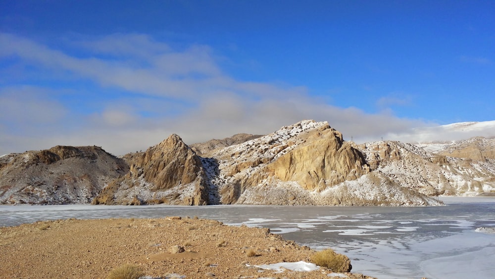 a snowy mountain range with a lake in the foreground