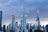 A dramatic skyline featuring several modern skyscrapers under a cloudy sky. The architecture is sleek and contemporary, with the tallest building having two prominent golden horizontal structures. The cityscape reflects a sense of urban growth and advancement.