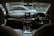 The interior of a modern car featuring a sleek dashboard design with an infotainment system, climate controls, and a leather-wrapped steering wheel. The front seats are visible, and the view through the windshield shows another car passing by on the road outside.