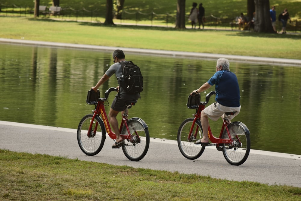 a couple of people riding bikes next to a body of water