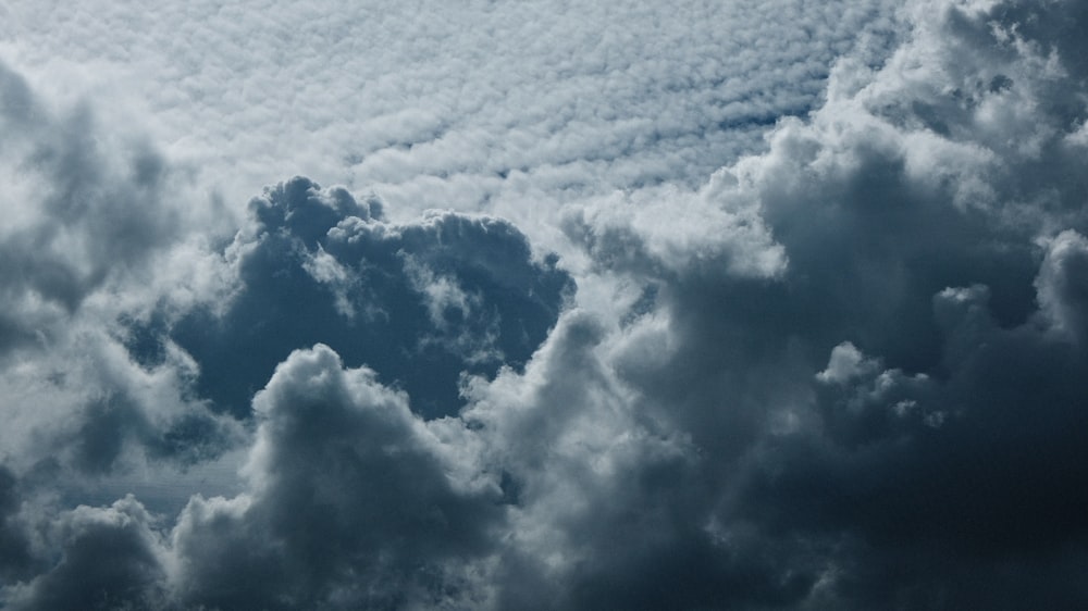 a plane flying through a cloudy blue sky