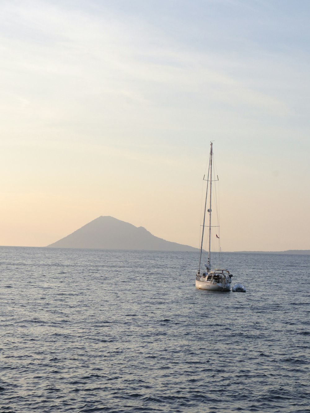 a sailboat in the ocean with a mountain in the background
