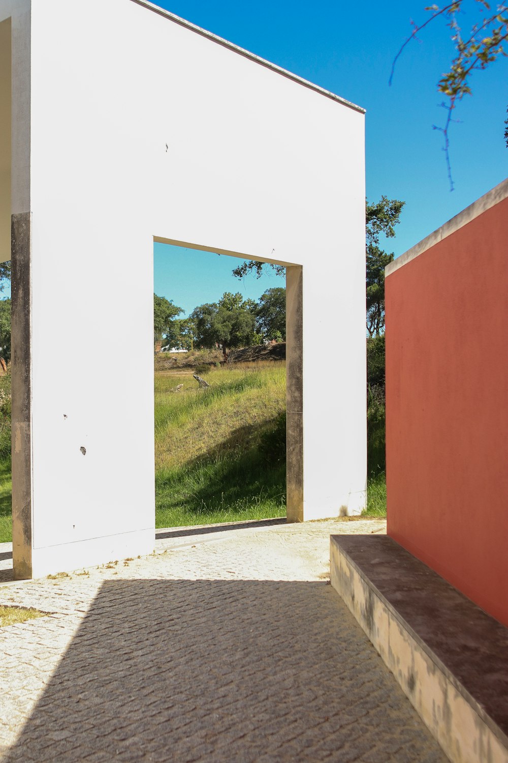 a white building with a red wall and a wooden bench