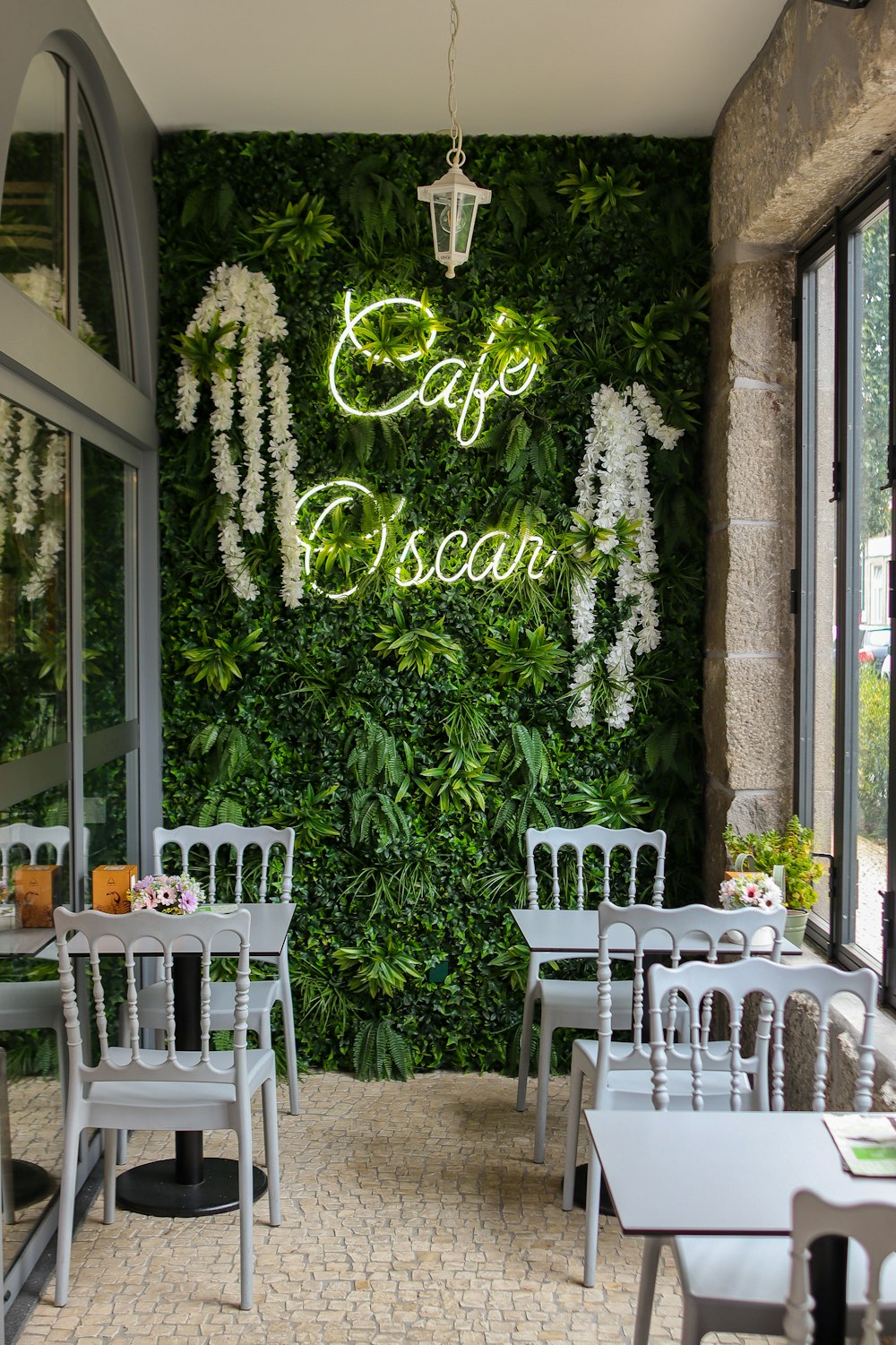 un restaurant avec un mur végétal et des chaises blanches