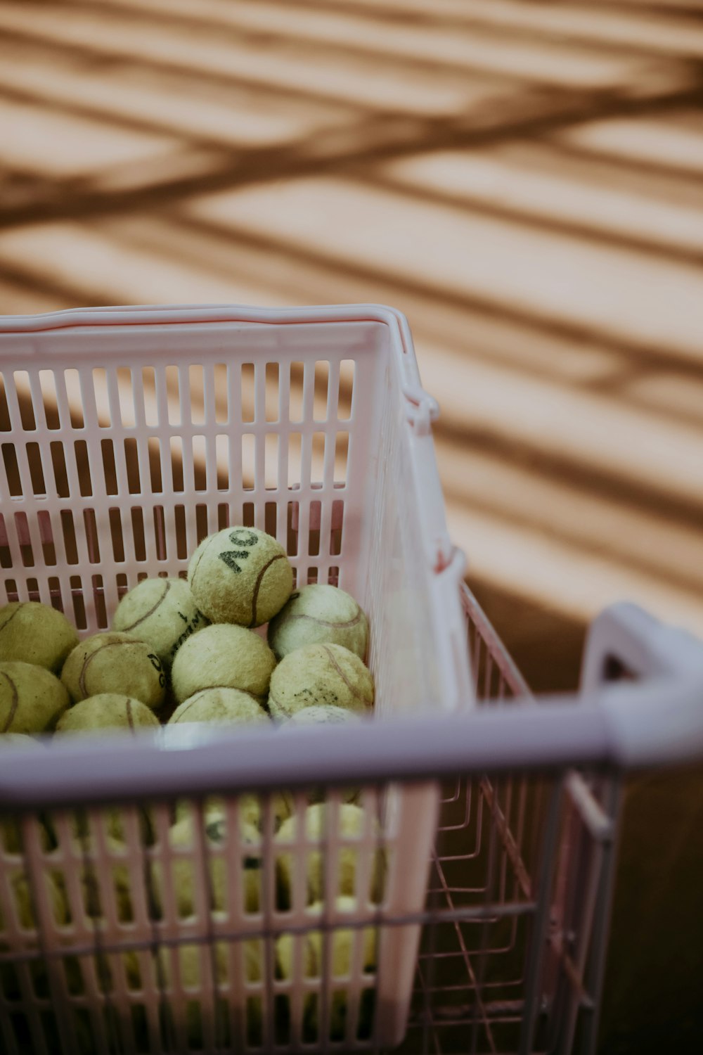 a basket filled with tennis balls on top of a wooden floor