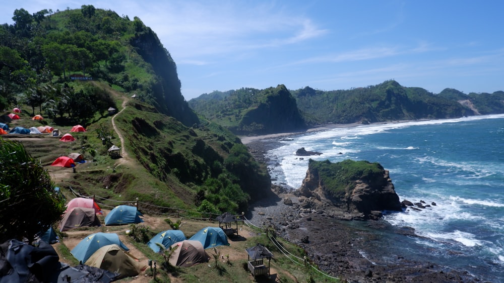 a group of tents set up on a cliff next to the ocean