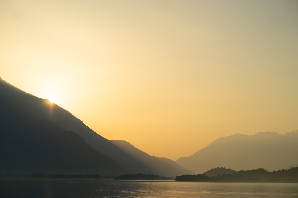 the sun is setting over a mountain range