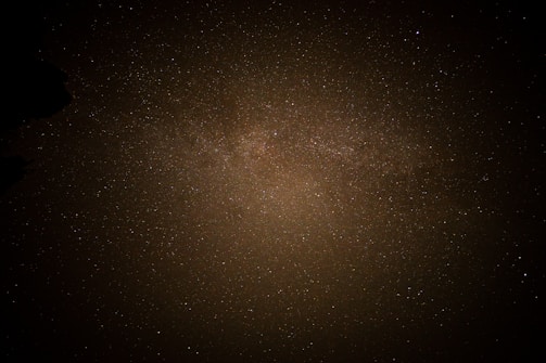 A vast expanse of the night sky filled with countless stars. The stars, varying in brightness, form a dense cluster, possibly part of the Milky Way galaxy. The image conveys a sense of the infinite and the mysterious nature of the universe.