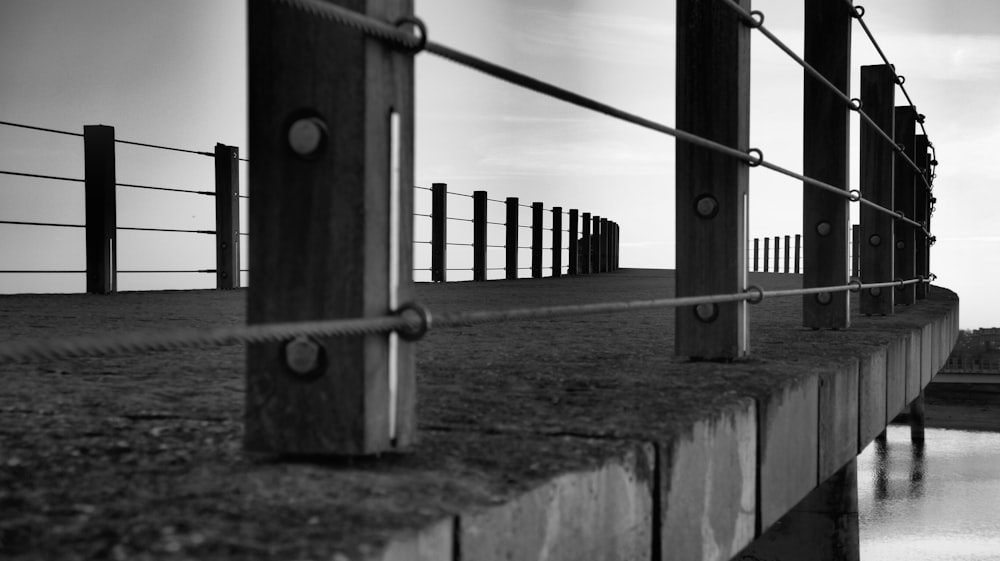 a black and white photo of a fence and a body of water