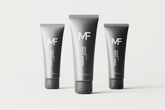 Three black tubes of different sizes are arranged on a plain background. Each tube is labeled with the letters 'MF' and the words 'black tube mockups' in white text. The tubes are cylindrical with flat caps and appear to be standing upright.