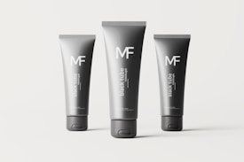 Three black tubes of different sizes are arranged on a plain background. Each tube is labeled with the letters 'MF' and the words 'black tube mockups' in white text. The tubes are cylindrical with flat caps and appear to be standing upright.