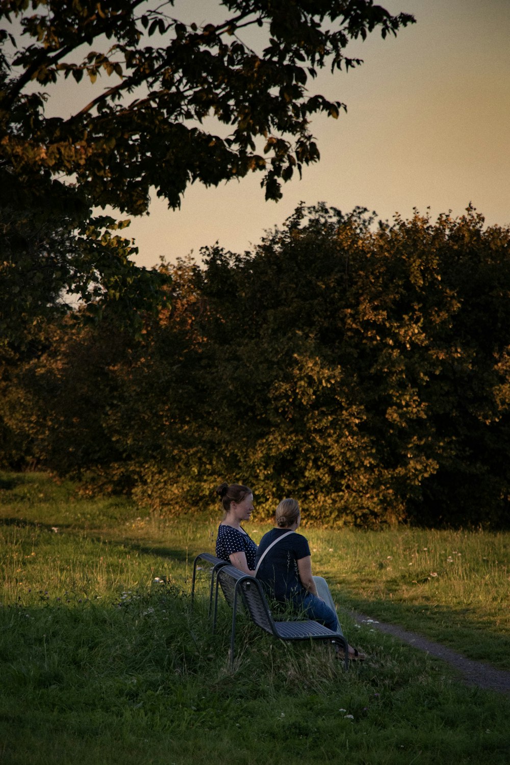 a couple of people sitting on top of a grass covered field