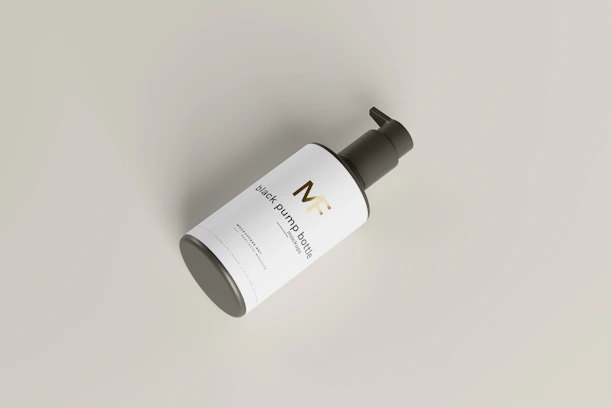 A black pump bottle is placed at an angle against a light gray background. The bottle has a sleek design with a white label featuring gold and black text. The pump top is black and contrasts with the clean and minimalist look of the label and bottle.