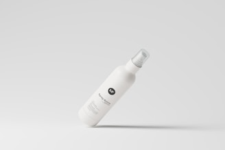 A floating white spray bottle with a simple, minimalist design is centrally positioned against a light gray background. The label features a circular logo with the letters 'NF' and the text 'Spray Bottle' beneath it.