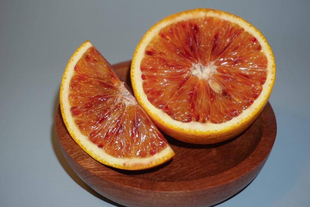 a grapefruit cut in half on a wooden plate