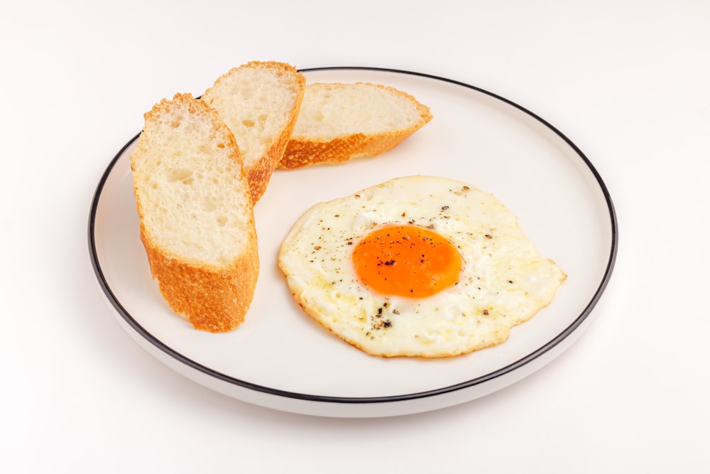 a white plate topped with a fried egg and slices of bread