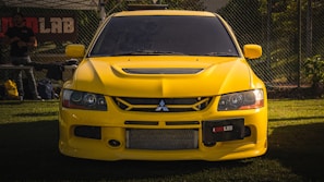 a yellow car is parked in the grass