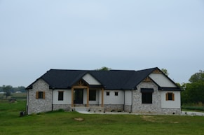 a stone house with a black roof and windows