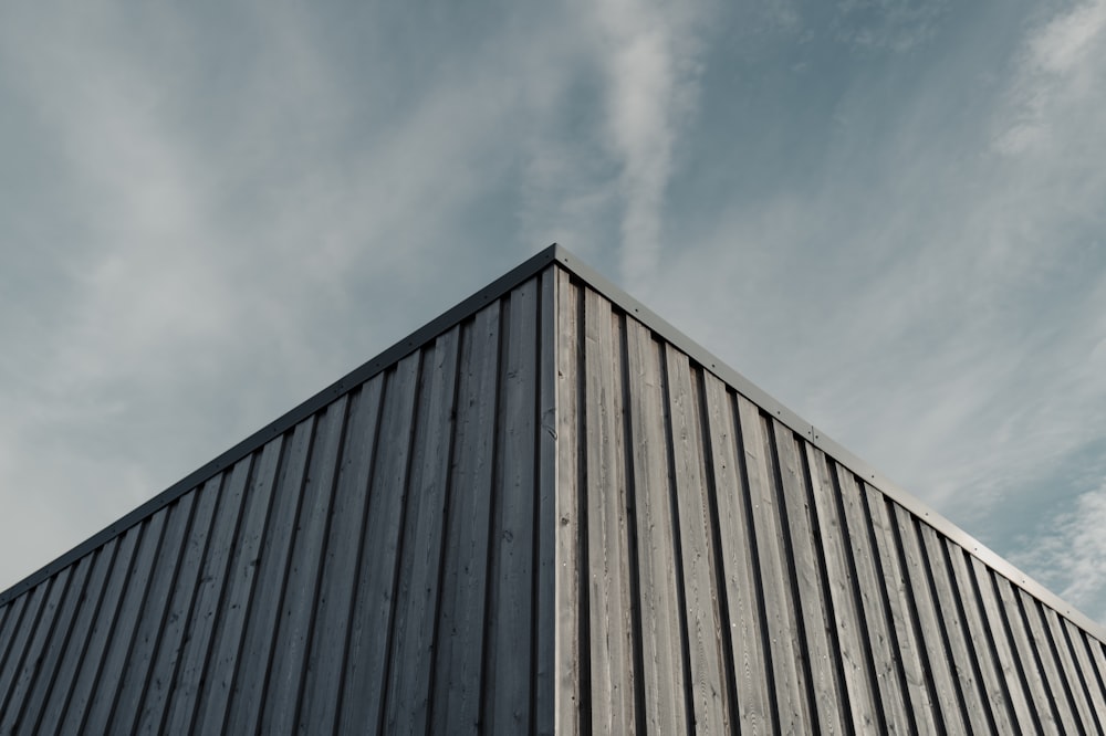 Un edificio alto con un techo de metal bajo un cielo azul nublado