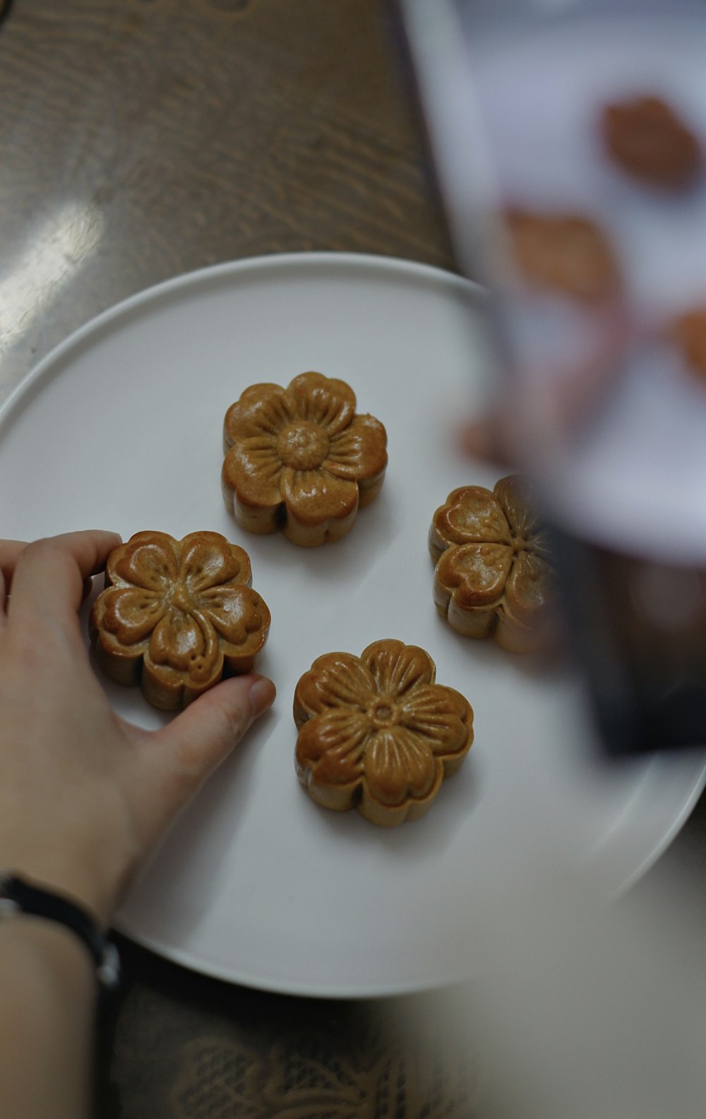 a person holding a plate with four cookies on it