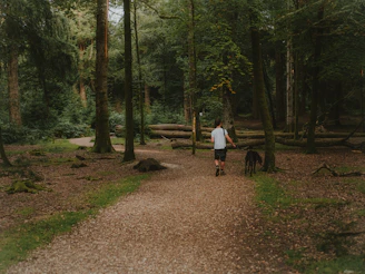 A happy woman walking her dog along a quiet forest path near the accommodation.