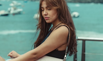 a woman holding a white purse on top of a pier