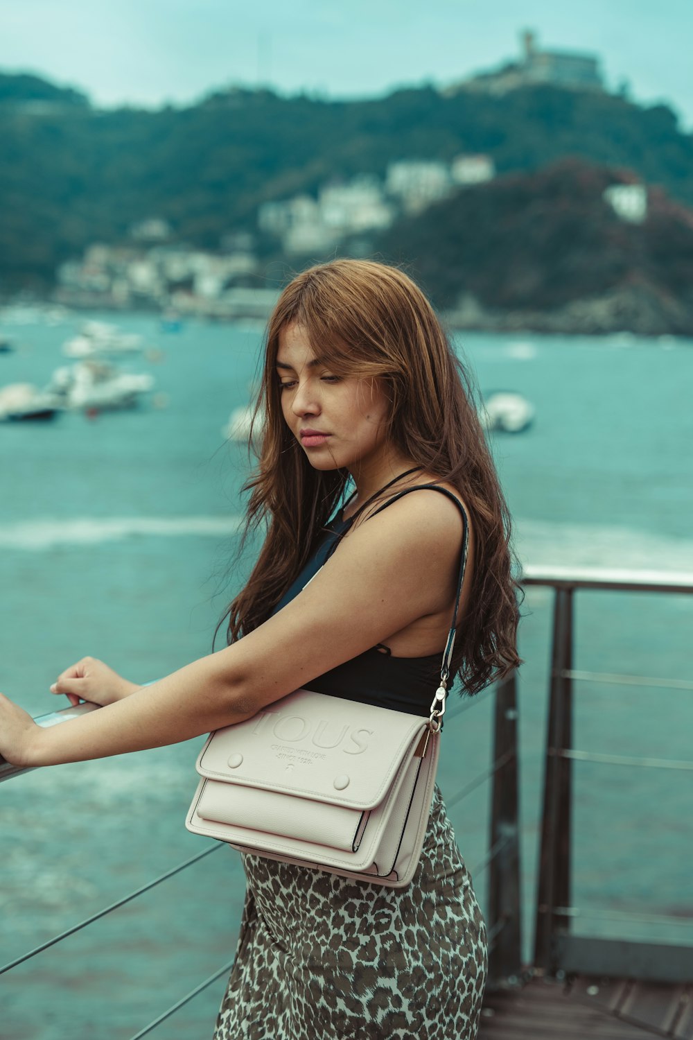 uma mulher segurando uma bolsa branca em cima de um píer