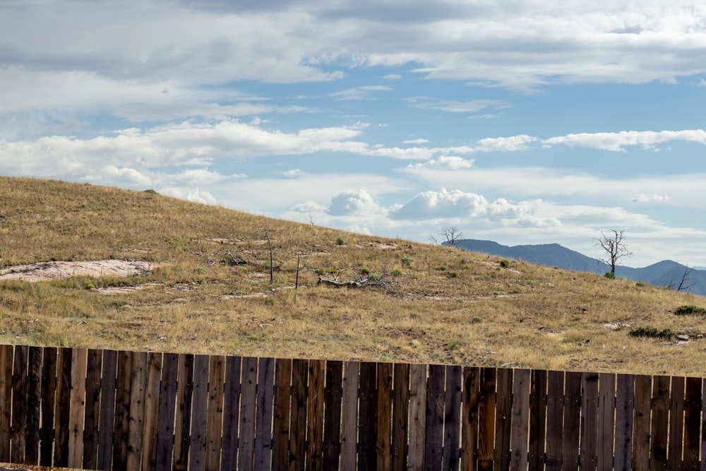 a wooden fence sitting on top of a grass covered hillside