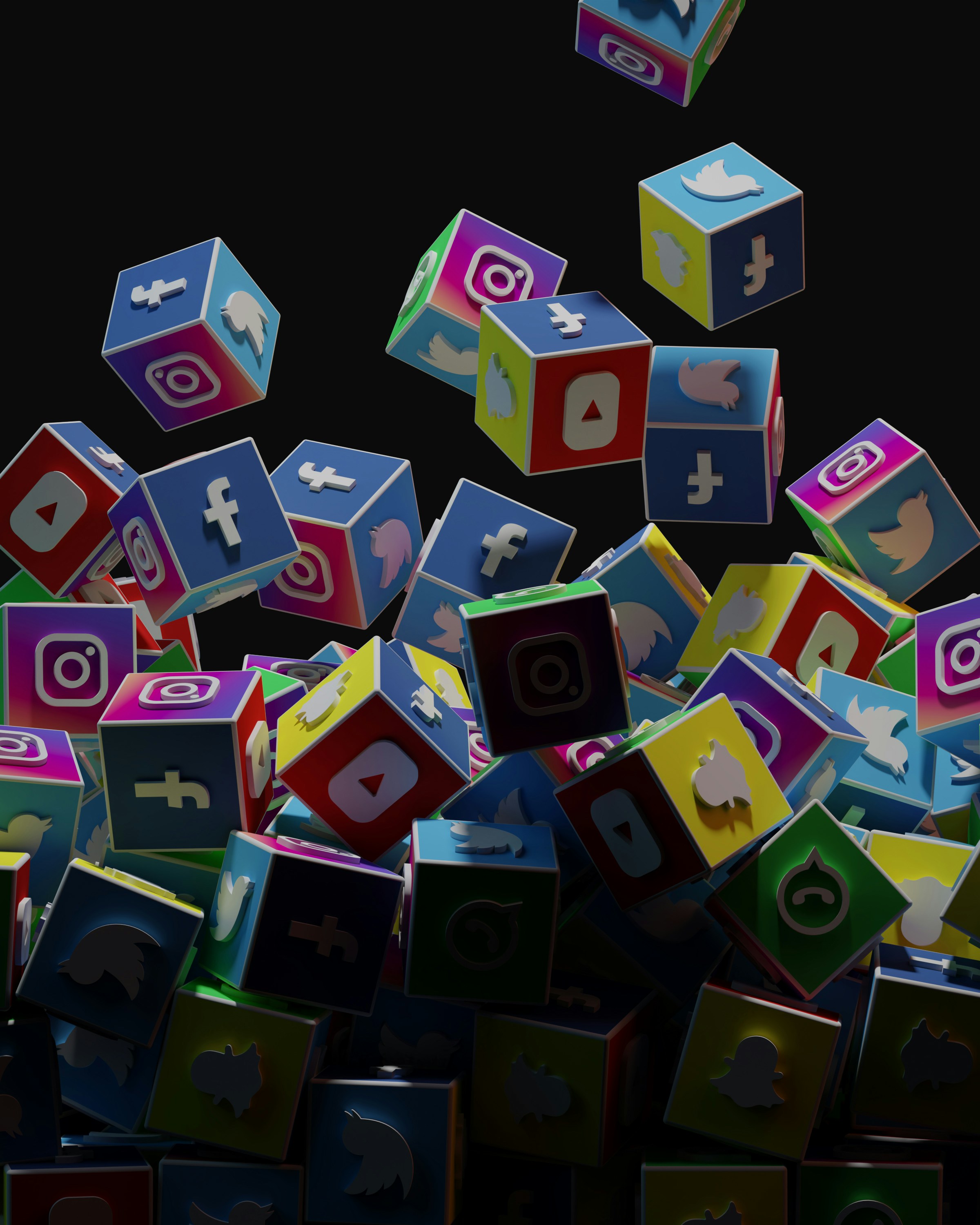 A collection of colorful 3D cubes displaying logos of various social media platforms, including Facebook, Instagram, Twitter, YouTube, and others. The cubes appear to be falling and tumbling over each other against a dark background.