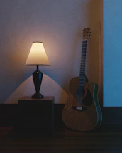 A rustic wooden table with a vintage microphone and guitar leaning against it, bathed in warm, golden light.