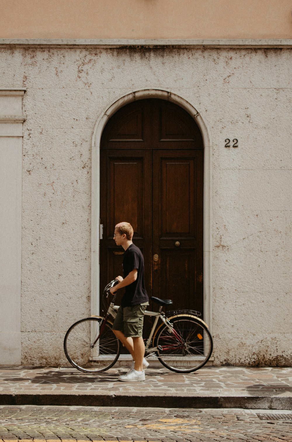 a man walking a bike past a doorway