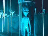 an alien doll is standing in a glass tube