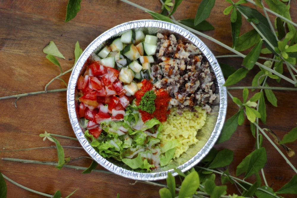 a metal bowl filled with different types of vegetables