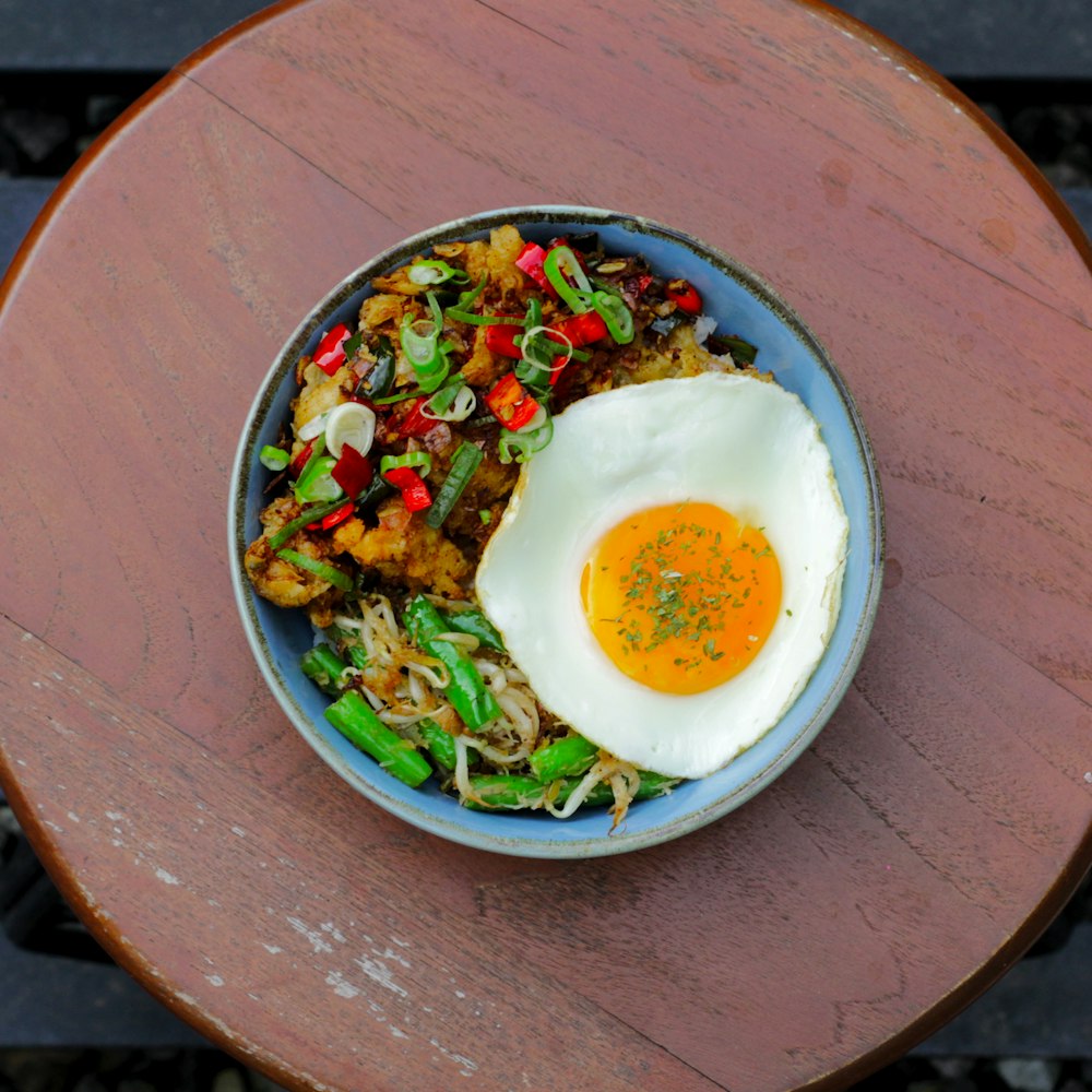 a bowl of food with an egg on top of it