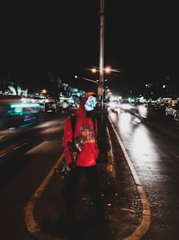 Person wearing a glowing hoodie walking down a city street at dusk