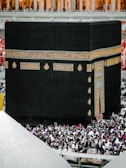 The Kaaba surrounded by worshippers in a vibrant atmosphere.