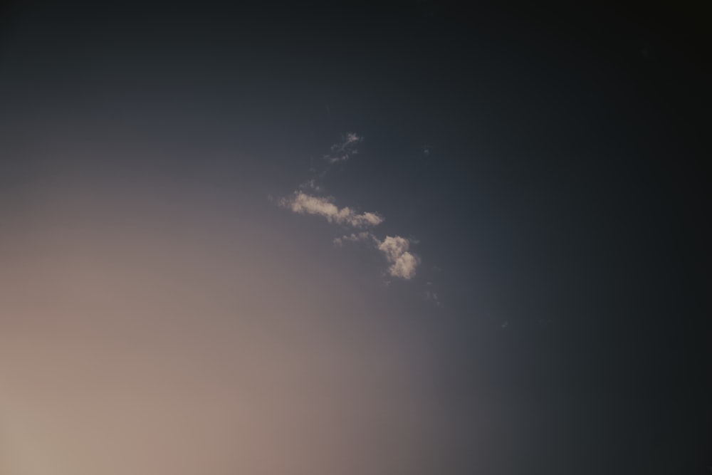 a plane flying in the sky with a cloud in the background