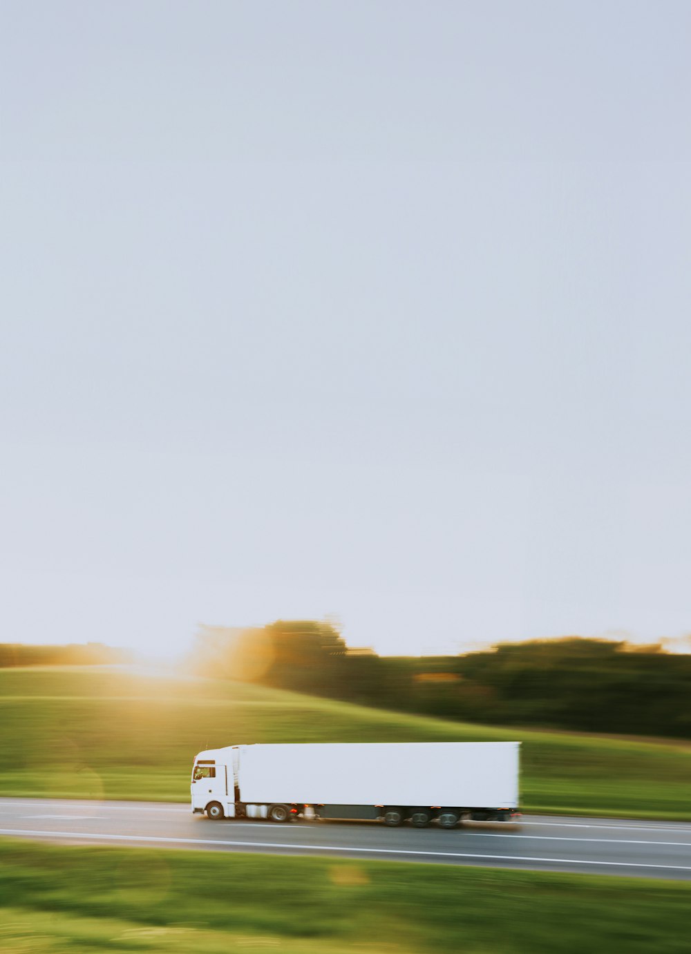 a white truck driving down a road next to a lush green field