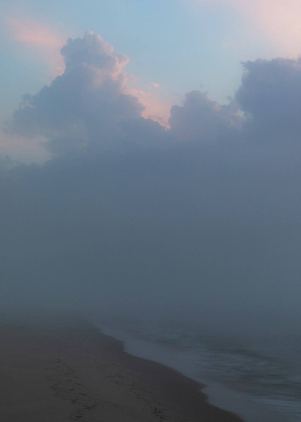 a foggy day at the beach with footprints in the sand