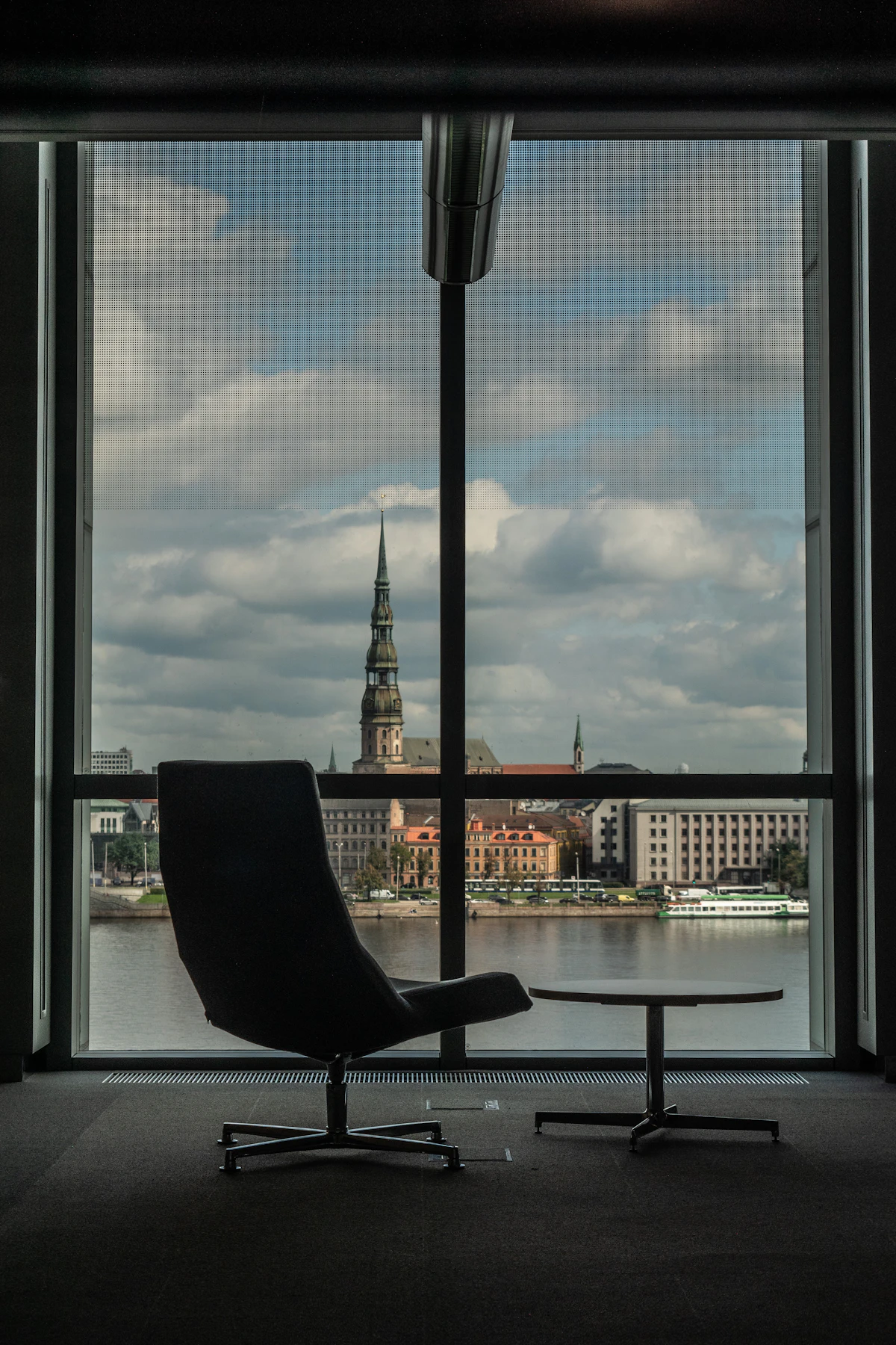 A quiet office chair positioned before a window overlooking the city at dusk