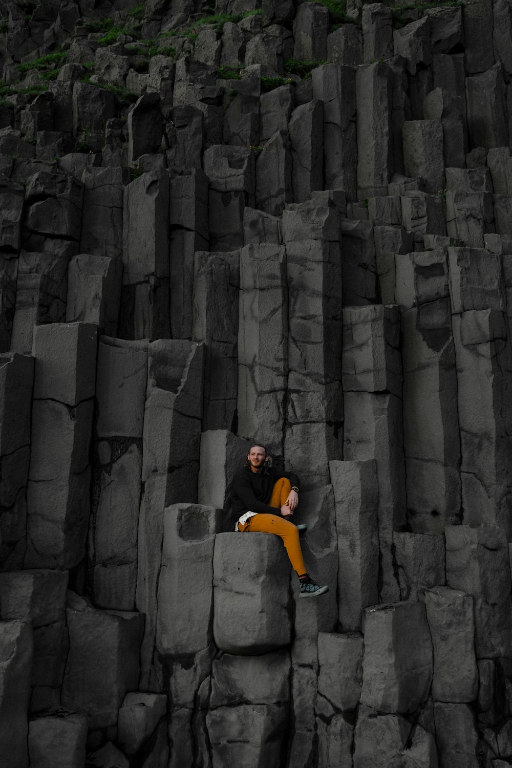um homem sentado em cima de uma formação rochosa