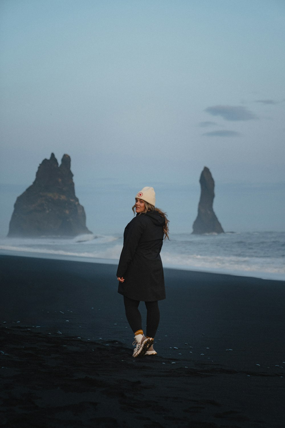 a woman standing on a beach next to the ocean