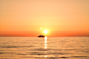 a boat in the ocean during a sunset