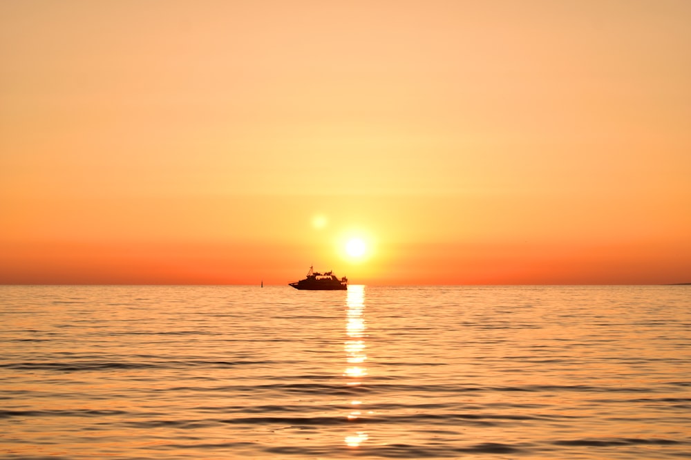 a boat in the ocean during a sunset