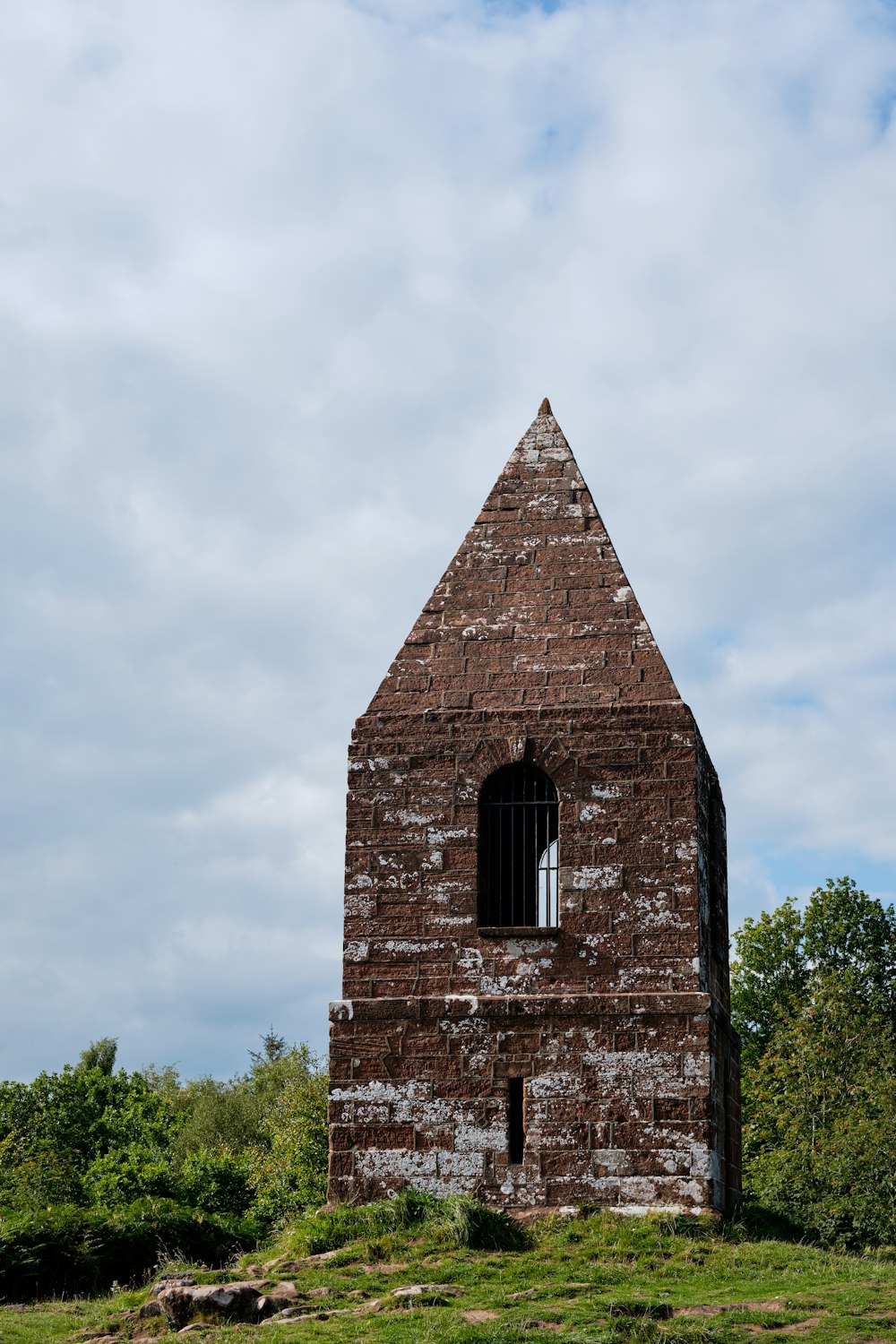 an old brick building sitting on top of a lush green field