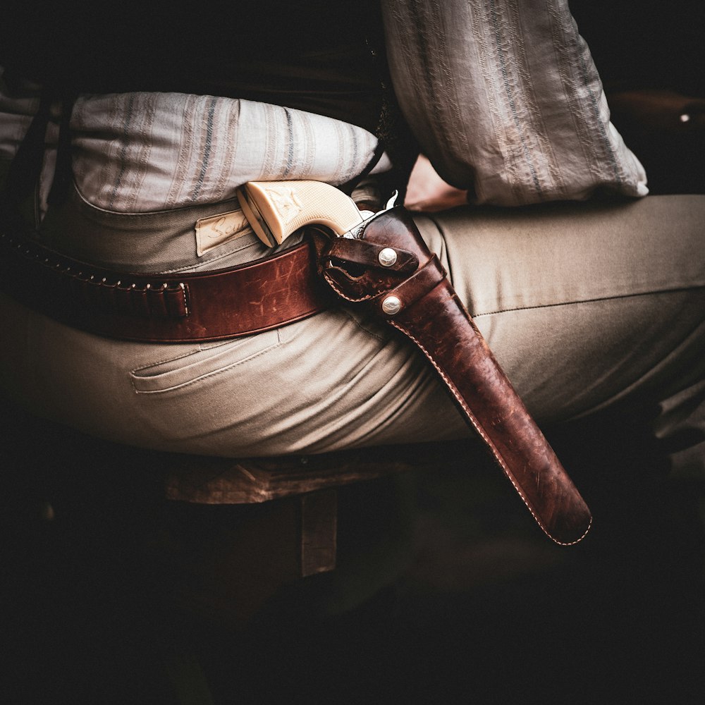 a person sitting on a stool with a leather belt