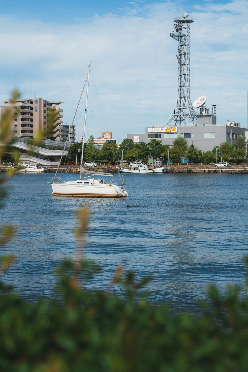 a sailboat in the water with a city in the background