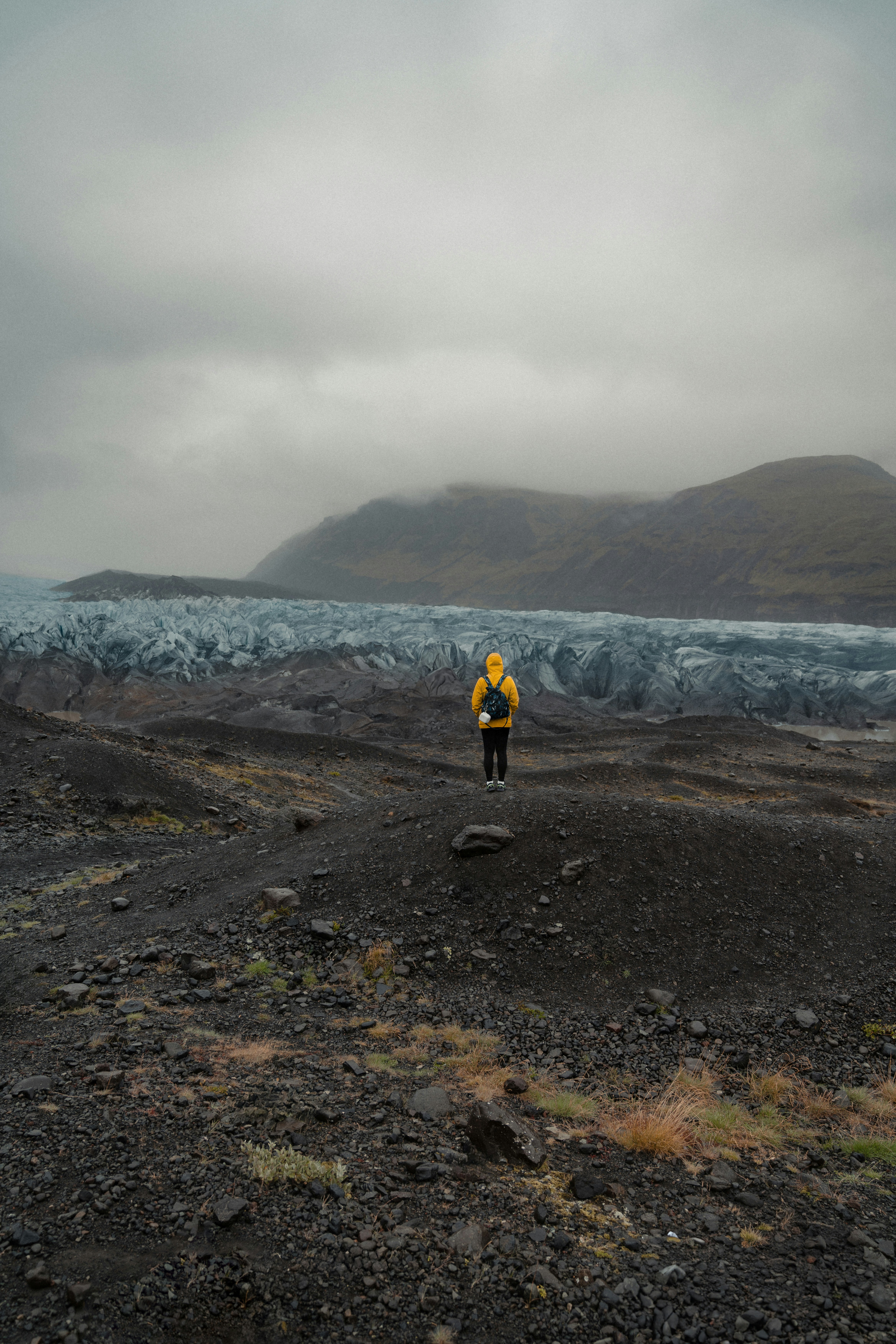 a man in a yellow jacket standing on a rocky beach