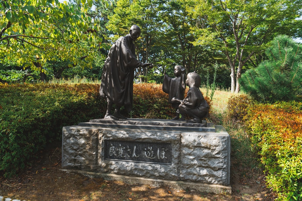 a statue of a man and two dogs in a park